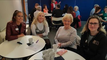 Four female attendees at the Dementia Cafe enjoying some coffee and tea.