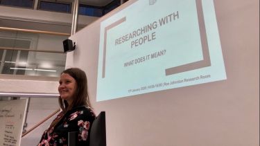 PhD student Hannah presents in front of projector screen