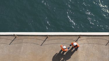 Overhead view of Caucasian technicians shaking hands near water