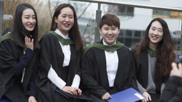 A group of students posing for a photo. They are all wearing their graduation robes.
