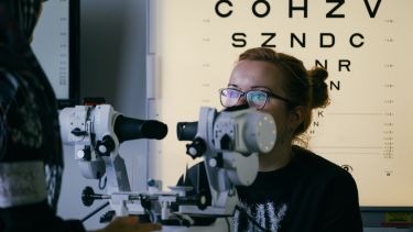 Orthoptics students inspecting eyes using a machine. 