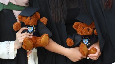 Teddy bear souvenirs being held by students. 