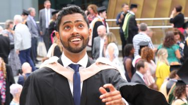 A male undergraduate student throws his hat outside the Student Union. 