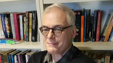 Honorary Reader Keith Frankish stood in front of a bookshelf