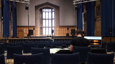 A man sat in Firth Hall working on some software on a laptop