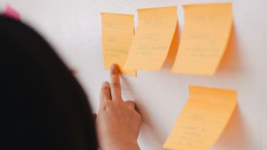 Person pointing to post-it notes on a wall