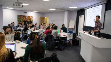 A lecture being delivered in the School of Health and Related Research. The academic stands at the front of the class and points to a presentation.