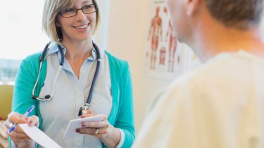 A nurse and patient. She is showing the patient a piece of paper.