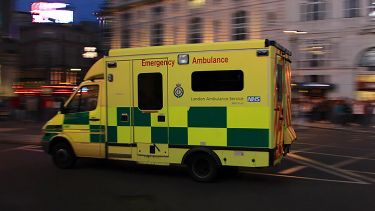 An ambulance speeds through London's Piccadilly Circus. "Day 2 - England 52" by Mike Miley is licensed under CC BY-SA 2.0