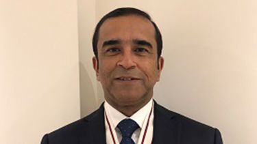 A profile shot of Professor Jaydip Ray. He is wearing a suit and is smiling. 