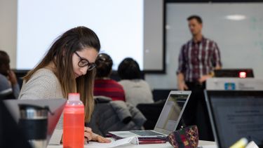 A female student in the School of Health and Related Research takes notes in a lecture.
