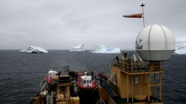 A ship facing multiple icebergs on the ocean
