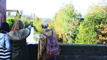 Students standing on bridge pointing at something in the distance