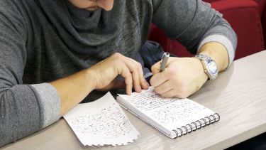A journalism student writing shorthand in a notebook.