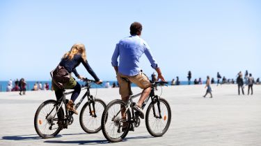 Two people cycling on sea front