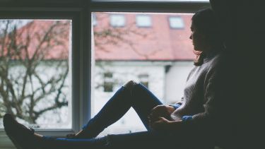 Woman sat in window. Image courtesy of Pixabay.