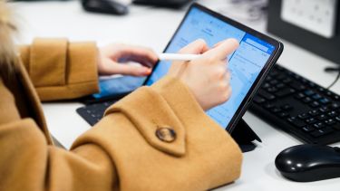 An Information School student writing with a stylus on a tablet. 