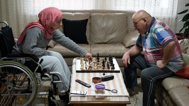 A woman and her grandfather playing chess in a living room