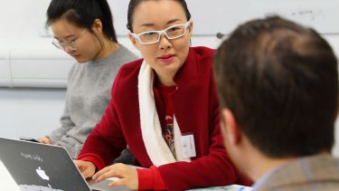 A postgraduate research student having a conversation and making notes.