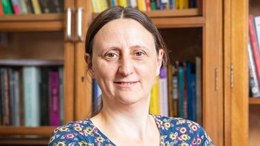 A photo of Professor Sarah Whitehouse sitting in front of a bookshelf