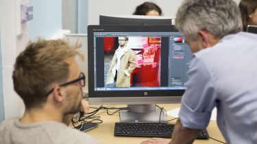 A student using Photoshop and receiving guidance from the lecturer. 