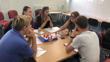 Students sitting round a table using game counters