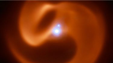 Spectacular star system wrapped in elegant spiral dust cloud