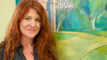 Dr Fuschia stood in front of a landscape painting