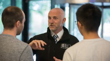 A member of security talking to two students