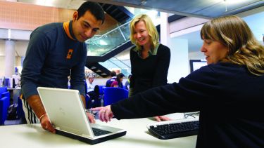 An image of staff helping a student at an information desk.