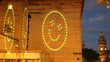 The Happy Sheffield logo projected onto Sheffield City Hall