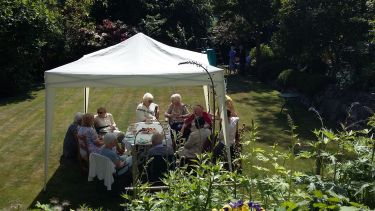 members of the women's club sat under a gazebo having coffee
