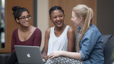 Three females students chatting together with a laptop