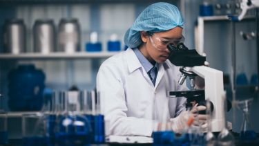 Young scientist working with a microscope in a laboratory. Young scientist doing some research.
