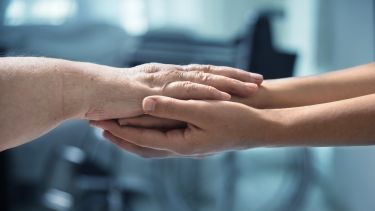 Photo of a young and older person's arms stretched out to lay the older person's arms across the younger arms.