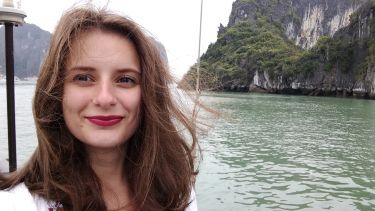 Graduate Chloe Young on a boat set against mountainous terrain