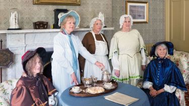 members of the women's club dressed up in Victorian clothing having tea