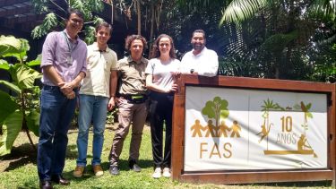 a group of people stand in a green forest in front of sign