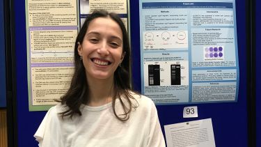 Eleni stands in front of her poster exhibition at the University
