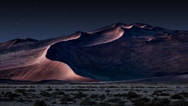 Desert of namib at night with orange sand dunes and starry sky