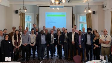 Attendees of the AREC workshop stood together in front of a powerpoint presentation