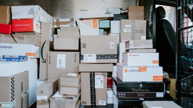 Back of a delivery van stacked high with brown cardboard boxes