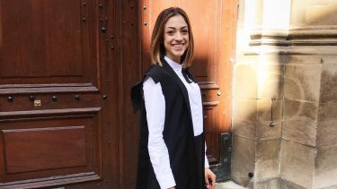 Melis in front of a grand building at the University of Oxford