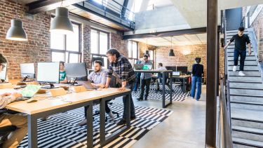 An open plan work place with employees working on computers.