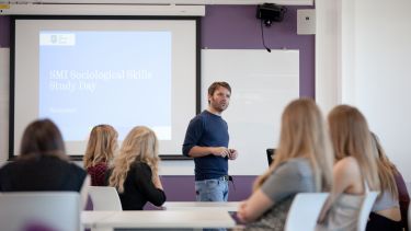 A lecturer delivers a presentation to a classroom of students