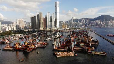 A view of a busy industrial port in Hong Kong with the International Commerce Centre in the background