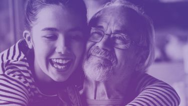 A girl is hugging an older man. They are both smiling. The image has a purple-blue filter