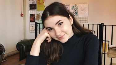 Image of Andreea, politics student ambassador, sat at a desk with a notepad and a cup of tea