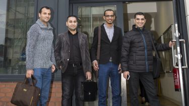 A group of four male students stood outside the entrance to the English Language Teaching Centre building.