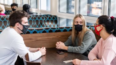 3 students socialising in the edge bar with face coverings